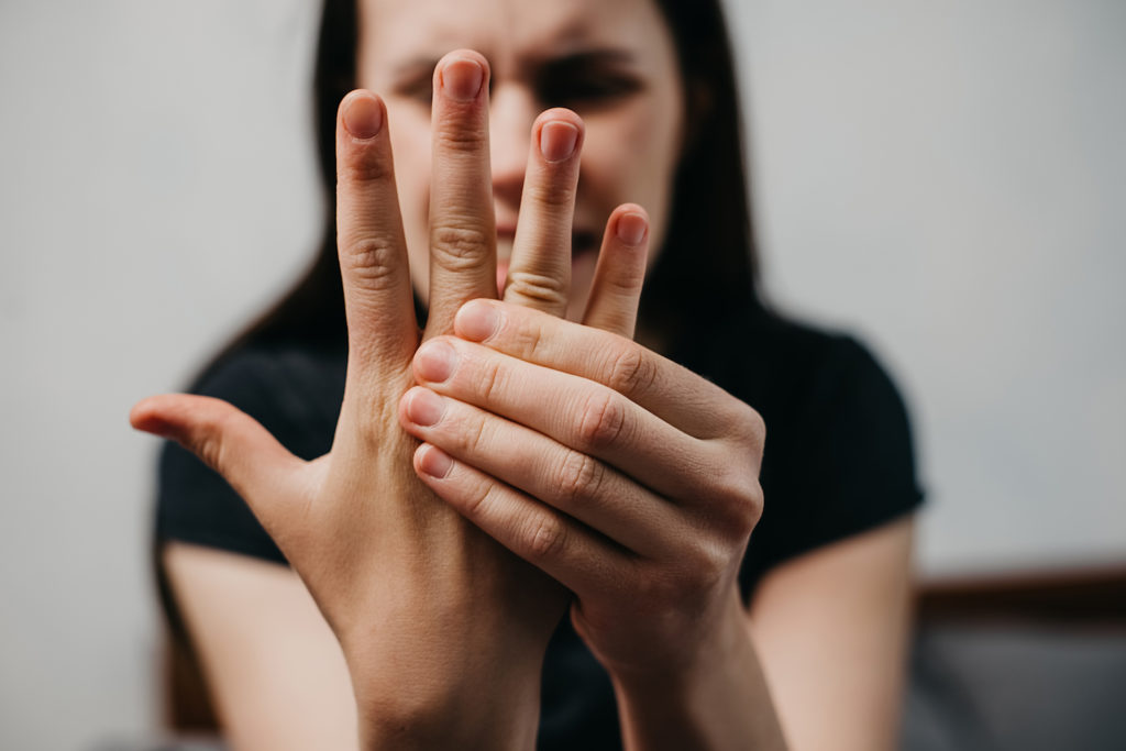 woman holding her hand due to neuropathy pain