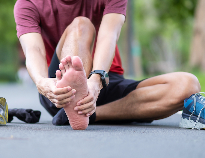 man holding his foot in pain due to plantar fasciitis pain