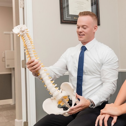 cropped image of dr. Henricksen holding a spine model