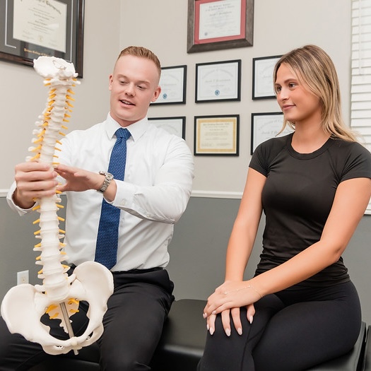 dr. Henricksen holding a full spine model showing to patient